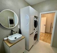 PREDAJ - 2-izbový byt v nádhernej lokalite Dvorníky - Kúpeľňa v 2-izbovom byte s práčkou, sušičkou a umývadlom na drevenom dekore.