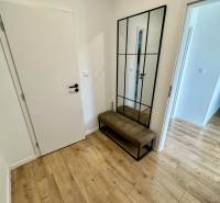 PREDAJ - 2-izbový byt v nádhernej lokalite Dvorníky - Chodba s podlahou s dreveným dekorom, lavicou a veľkým zrkadlom v 2-izbovom byte.