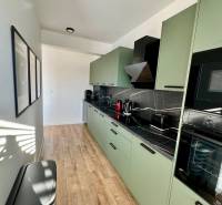 PREDAJ - 2-izbový byt v nádhernej lokalite Dvorníky - Kuchyňa v 2-izbovom byte s podlahou s dreveným dekorom a zelenými skrinkami.