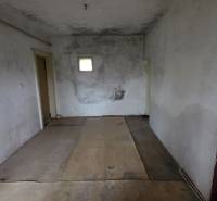 Na predaj 5 izbový rodinný dom Vinohrady nad Váhom - Opustená miestnosť v rodinnom dome so starými stenami a malým oknom.