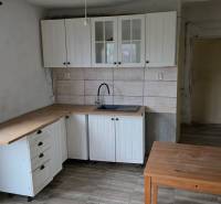 Na predaj 5 izbový rodinný dom Vinohrady nad Váhom - Kuchyňa v rodinnom dome s bielymi skrinkami a podlahou s dreveným dekorom.