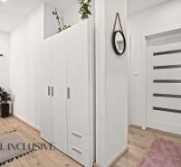 REZERVOVANÉ | NA PREDAJ 3-IZBOVÝ BYT S BALKÓNOM, VRAKÚŇ - Predsieň v 3-izbovom byte s bielou skriňou, podlahou s dreveným dekorom a zelenými rastlinami.