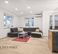 REZERVOVANÉ | NA PREDAJ 3-IZBOVÝ BYT S BALKÓNOM, VRAKÚŇ - Obývačka 3-izbového bytu s podlahou s dreveným dekorom, pohodlným sedením a veľkými oknami.