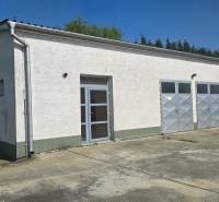 Prenájom haly v Šali – Veča | 220 m² | Ideálne na podnikanie - Biela budova s kovovými dverami v skladovej a halovej zóne mesta Šaľa.