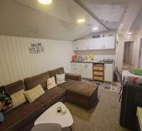 Pohoda pri vode, chata s výhľadom na Domašu - Obývacia izba v chate s pohodlnou sedačkou, kuchynskou linkou a dekoratívnym obkladom na stene.