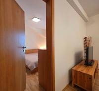 Apartmán, Nová Lesná, 46m2 + balkón, park. miesto, zariadený  - Rekreačný apartmán s podlahou s dreveným dekorom, pohľad na spálňu a obývaciu stenu.