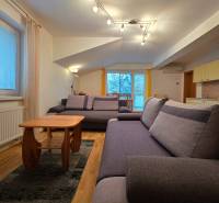 Apartmán, Nová Lesná, 46m2 + balkón, park. miesto, zariadený  - Svetlá obývačka v Rekreačnom apartmáne s pohodlnými sedačkami a podlahou s dreveným dekorom.