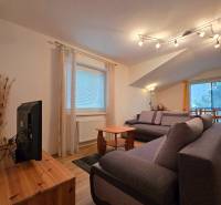 Apartmán, Nová Lesná, 46m2 + balkón, park. miesto, zariadený  - Obývacia izba v Rekreačnom apartmáne s pohodlnými pohovkami a podlahou s dreveným dekorom.