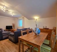 Apartmán, Nová Lesná, 46m2 + balkón, park. miesto, zariadený  - Obývacia izba v Rekreačnom apartmáne s podlahou s dreveným dekorom, sedačkou a jedálenským stolom.