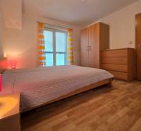 Apartmán, Nová Lesná, 46m2 + balkón, park. miesto, zariadený  - Spálňa v rekreačnom apartmáne s podlahou s dreveným dekorom, posteľou a skriňou.