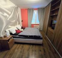 Predaj,trojizbový byt SNP, Holíč - Spálňa s posteľou, vstavanými skriňami a podlahou s dreveným dekorom v 3-izbovom byte.