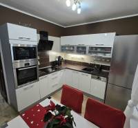 Predaj,trojizbový byt SNP, Holíč - Kuchyňa v 3-izbovom byte s bielymi skrinkami, nerezovými spotrebičmi a dekoráciou na stole.