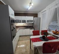 Predaj,trojizbový byt SNP, Holíč - Kuchyňa v 3-izbovom byte s lesklými bielymi skrinkami, spotrebičmi a jedálenským stolom.