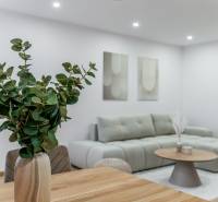 MICHALOVSKÁ:  moderný 3 izb. byt. REKONŠTRUKCIA, ZARIADENIE, LOGGIA.  - Obývacia časť 3-izbového bytu s pohovkou, stolom a kvetmi v svetlých odtieňoch.