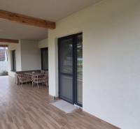 Na predaj 4 izbový RD v obci  Studienka, garáž, sauna, pozemok 719 m2 - Terasa rodinného domu v Studienke s hojdacou hojdačkou a nábytkom, podlaha s dreveným dekorom.