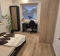 Na predaj 4 izbový RD v obci  Studienka, garáž, sauna, pozemok 719 m2 - Spálňa s posteľou, stolíkom a podlahou s dreveným dekorom v rodinnom dome.