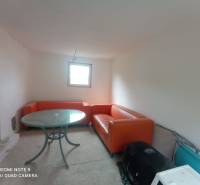 REZERVOVANÉ Chatka na krásnom mieste v kľudnom prostredí - Oranžové sedačky a okrúhly stôl dopĺňajú priestor v chate s bielymi stenami.