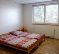 Ponúkame na predaj penzión v Poľnom Kesove - Pokoj s manželskou posteľou, podlahou s dreveným dekorom a moderným nábytkom v Hoteloch a penziónoch.