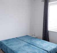 Ponúkame na predaj 3 izbový radový dom v obci Rastislavice. - Spálňa v rodinnom dome s modrými prehozmi na posteli a roletami.