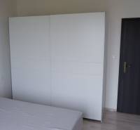 Ponúkame na predaj 3 izbový radový dom v obci Rastislavice. - Izba rodinného domu s posteľou, bielou skriňou a tmavými dverami.