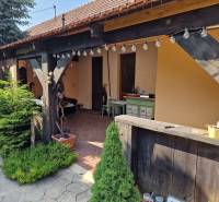 Krásny rodinný dom s rozľahlým pozemkom - Rodinný dom v Dlhej nad Váhom s terasou, drevenými prvkami a záhradnou výzdobou.