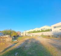 Rodinný dom s veľkým pozemkom v Kolárove –  na bývanie, podnikanie - Pohľad na rodinné domy v Kolárove s priľahlým priestranstvom a jasnou modrou oblohou.