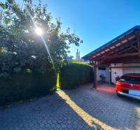 Domov, kde si vytvoríte vlastný príbeh – rodinný dom na predaj, Neded - Rodinný dom v Nedede s červeným autom pred garážou, slnečný deň a strom.