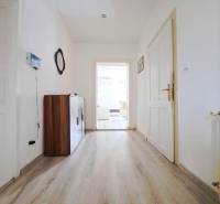 Domov, kde si vytvoríte vlastný príbeh – rodinný dom na predaj, Neded - Chodba v rodinnom dome s podlahou s dreveným dekorom a bielymi stenami.