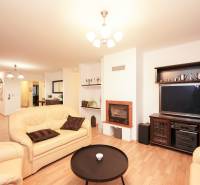 ViNi real / TOP PONUKA! Moderný 4-izb. bungalov s garážou, KVETOSLAVOV - Obývačka v rodinnom dome s krbom, koženými sedačkami a podlahou s dreveným dekorom.