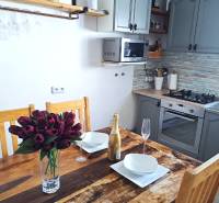 Exkluzívne na predaj 5 izbový rodinný dom - Kuchyňa v rodinnom dome s dreveným stolom, kvetmi, šampanským a kuchynskou linkou.