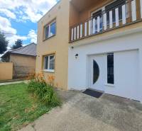 Exkluzívne na predaj 5 izbový rodinný dom - Rodinný dom vo Veľkej Mači s oranžovými kvetmi, zeleným trávnikom a vstupnými dverami.