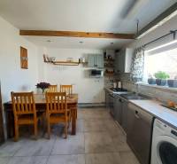 Exkluzívne na predaj 5 izbový rodinný dom - Kuchyňa v rodinnom dome s dreveným stropným trámom a sériou drevených stoličiek.