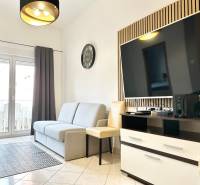 Trogir, Čiovo – pekný, zariadený apartmán len 150m od pláže - Obývacia izba s pohovkou a televízorom v rekreačnom apartmáne, svetlá dlažba, balkónové dvere.