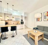 Trogir, Čiovo – pekný, zariadený apartmán len 150m od pláže - Rekreačný apartmán s kuchynským kútom, jedálenským stolom, sedačkou a umeleckými obrazmi na stene.