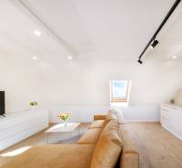  REZERVOVANY-PRENAJOM | NOVÝ 2 i. podkrovný byt v novostavbe - Svetlá obývacia izba s béžovou pohovkou, podlahou s dreveným dekorom a strešným oknom.