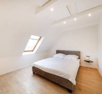  REZERVOVANY-PRENAJOM | NOVÝ 2 i. podkrovný byt v novostavbe - Svetlá spálňa s posteľou, strešným oknom a podlahou s dreveným dekorom v 2-izbovom byte.