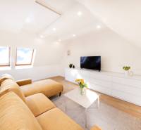  REZERVOVANY-PRENAJOM | NOVÝ 2 i. podkrovný byt v novostavbe - Obývačka v 2-izbovom byte s béžovou sedačkou, bielym nábytkom a podlahou s dreveným dekorom.