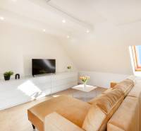  REZERVOVANY-PRENAJOM | NOVÝ 2 i. podkrovný byt v novostavbe - Obývacia izba v 2-izbovom byte s pohovkou, televízorom a strešným oknom, biela komoda.