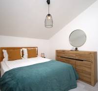 Vodice – novo zrekonštruovaný dvojspálňový apartmán s výhľadom na more - Spálňa v rekreačnom apartmáne s posteľou, drevenou komodou, zrkadlom a lampou.