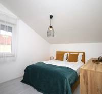 Vodice – novo zrekonštruovaný dvojspálňový apartmán s výhľadom na more - Spálňa v Rekreačnom apartmáne s manželskou posteľou, oknom a komodou pod šikmou strechou.