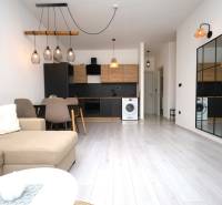 Vodice – novo zrekonštruovaný dvojspálňový apartmán s výhľadom na more - Obývacia izba Rekreačného apartmánu s kuchyňou, stolom, zrkadlom a podlahou s dreveným dekorom.