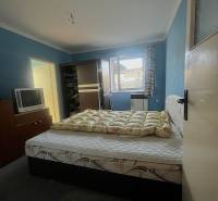 Znížená cena  4-izbový rodinný dom s veľkým pozemkom len 5min od Šale - Spálňa s posteľou, tmavým šatníkom, televízorom a modrými stenami v rodinnom dome.