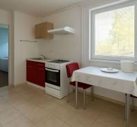 Znížená cena  4-izbový rodinný dom s veľkým pozemkom len 5min od Šale - Kuchyňa s červenou skrinkou, stolom a dvoma stoličkami v rodinnom dome.