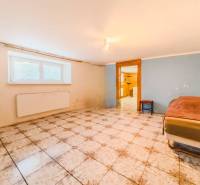 Rodinný dom vo vyhľadávanej obci Betliar. - Izba s dlažbou v rodinnom dome, posteľ pri stene, okno s radiátorom.