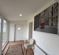 NA PRENÁJOM krásny 1 izbový apartmán so záhradou v srdci Komárna - Interiér 1-izbového bytu s podlahou s dreveným dekorom, sklenenými dverami a umením na stene.