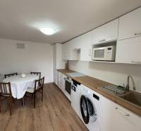 NA PRENÁJOM krásny 1 izbový apartmán so záhradou v srdci Komárna - Kuchyňa v 1-izbovom byte s podlahou s dreveným dekorom a jedálenským stolom.