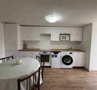 NA PRENÁJOM krásny 1 izbový apartmán so záhradou v srdci Komárna - Kuchyňa v 1-izbovom byte s bielymi skrinkami a podlahou s dreveným dekorom.