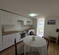 NA PRENÁJOM krásny 1 izbový apartmán so záhradou v srdci Komárna - Kuchyňa v 1-izbovom byte s podlahou s dreveným dekorom a jedálenským stolom.