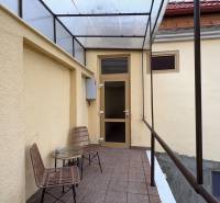 EXKLUZÍVNE na prenájom apartmán s nádychom afrického štýlu v centre KN - Kryté patio s dvoma stoličkami a stolíkom pred vstupom do 1-izbového bytu.