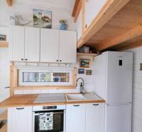 Tiny house - malý domček - Kuchyňa v rodinnom dome s bielymi skrinkami, dreveným dekorom a farebnou dlažbou.